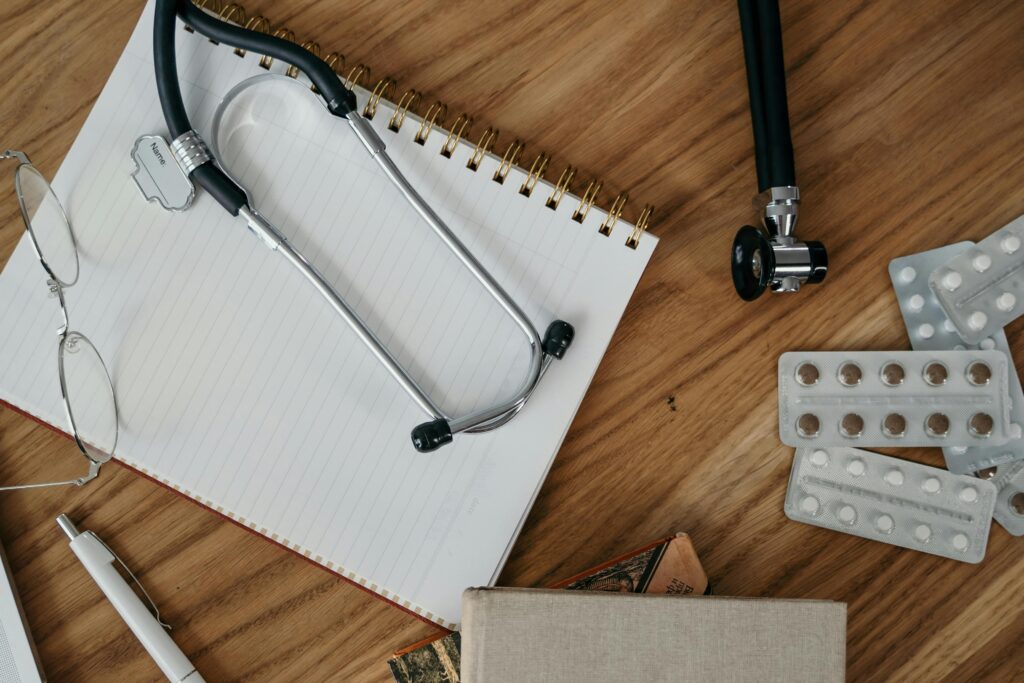 Fotografía de un estetoscopio, un cuaderno y pastillas